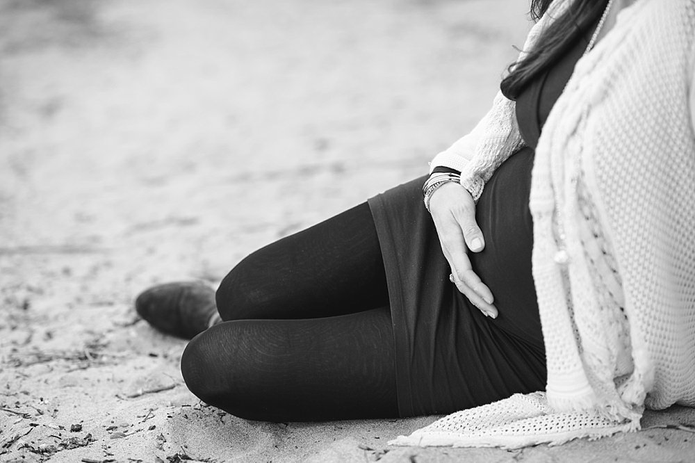 Schwangere Frau sitzt im Sand - schwarzweiß Foto