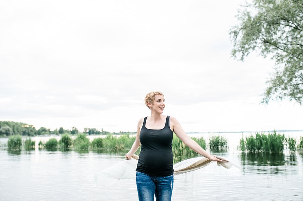 Kurzhaarige blonde Frau steht am Ufer des Bodensees