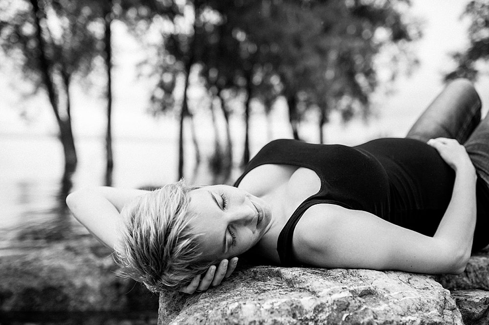 Junge Frau liegt entspannt auf einem Fels - schwarzweiß