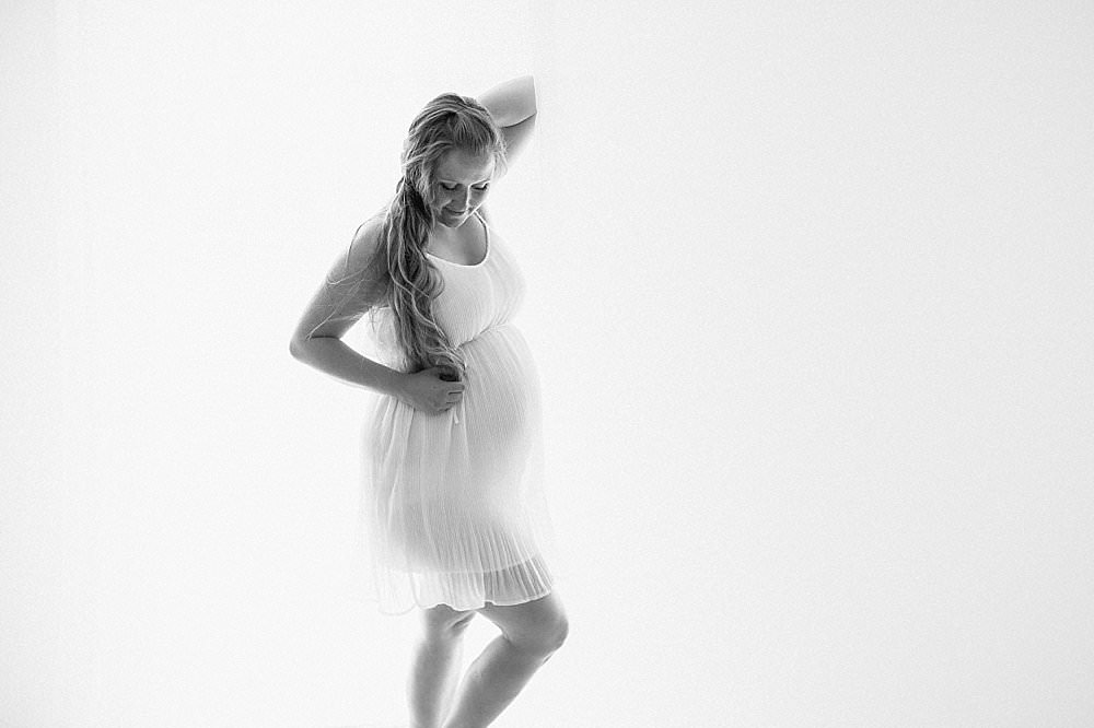 Werdende Mutter posiert in halbtransparentem weißen Kleid